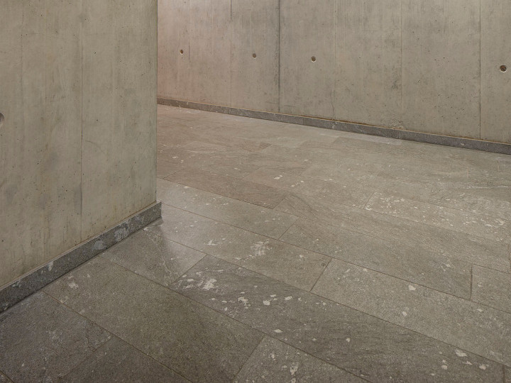 Natursteinboden aus San Berardino Silber geschliffen im Gang mit Sichtbeton in der Gemeindeverwaltung Meilen Zürich.