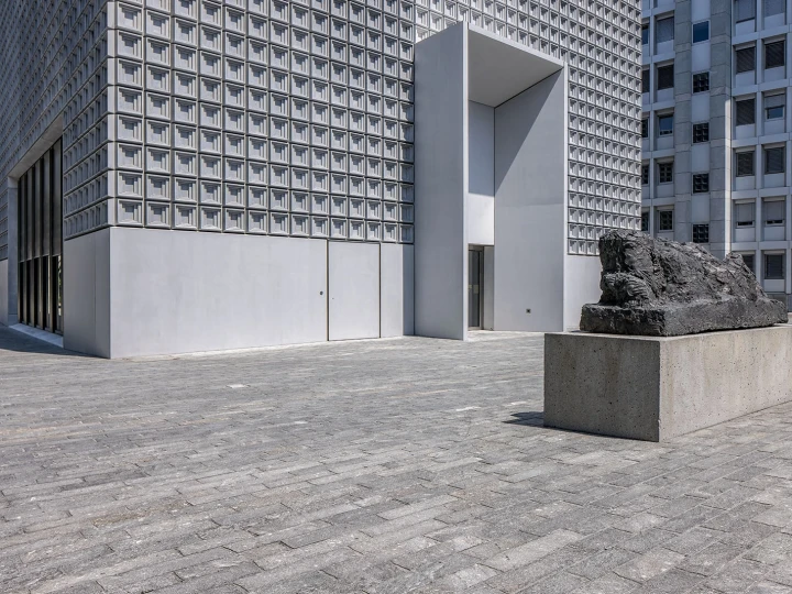 Skulptur auf Betonsockel inmitten der Platzpflästerung aus San Bernardino Silber beim Kunstmuseum Chur.