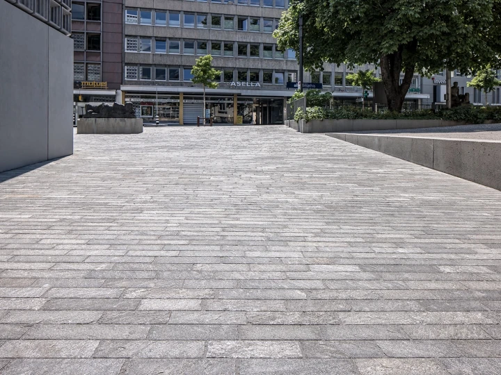 Reihenverlegte Bodenplatten San Bernardino Silber, gestrahlt, auf dem Platz beim Kunstmuseum Chur Richtung Stadt.